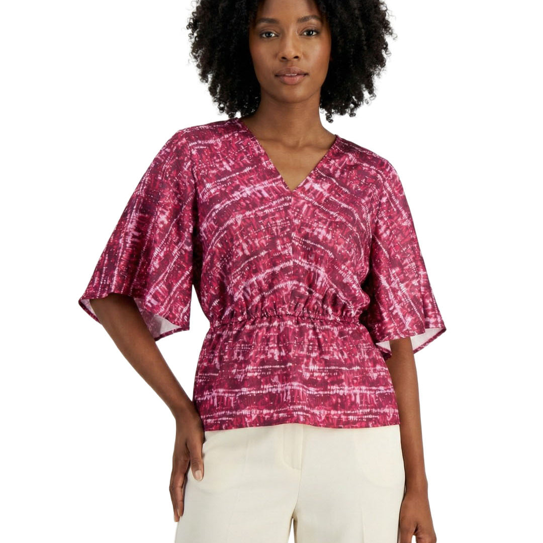 Woman wearing a pink patterned top and white pants on a white background