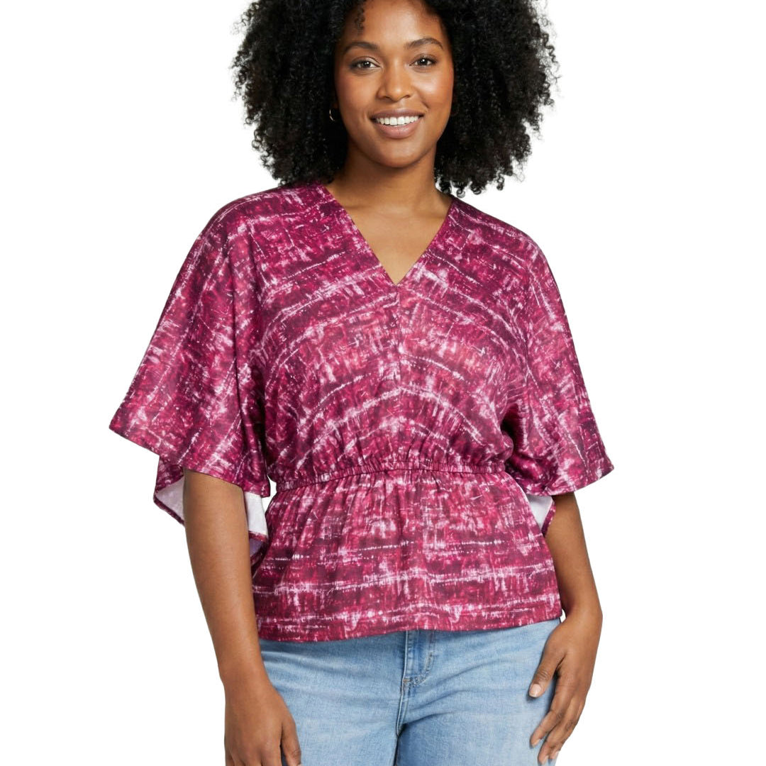 Woman wearing a pink tie-dye top and light blue jeans on a white background