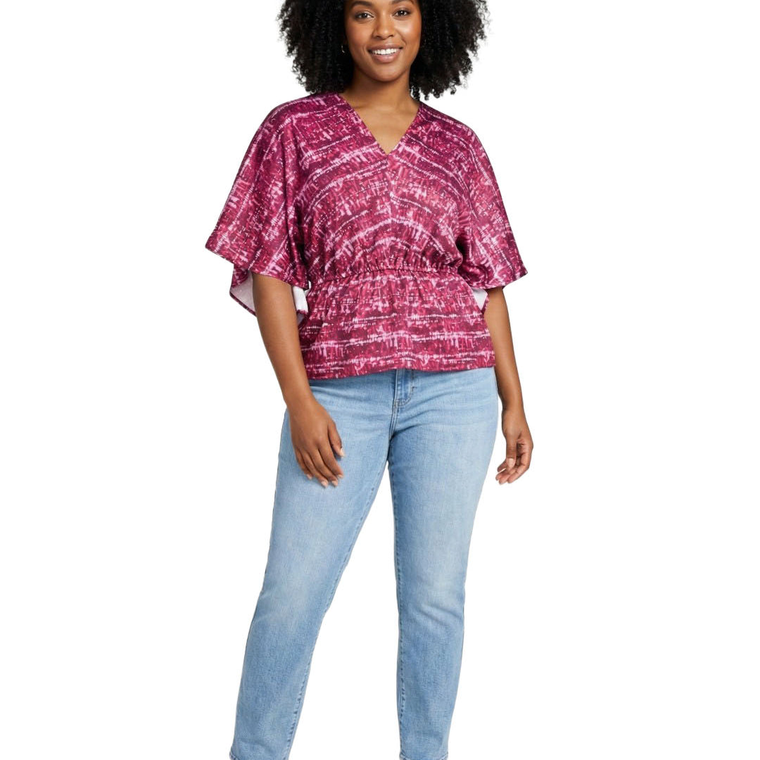 Woman wearing a pink patterned top and light blue jeans on a white background