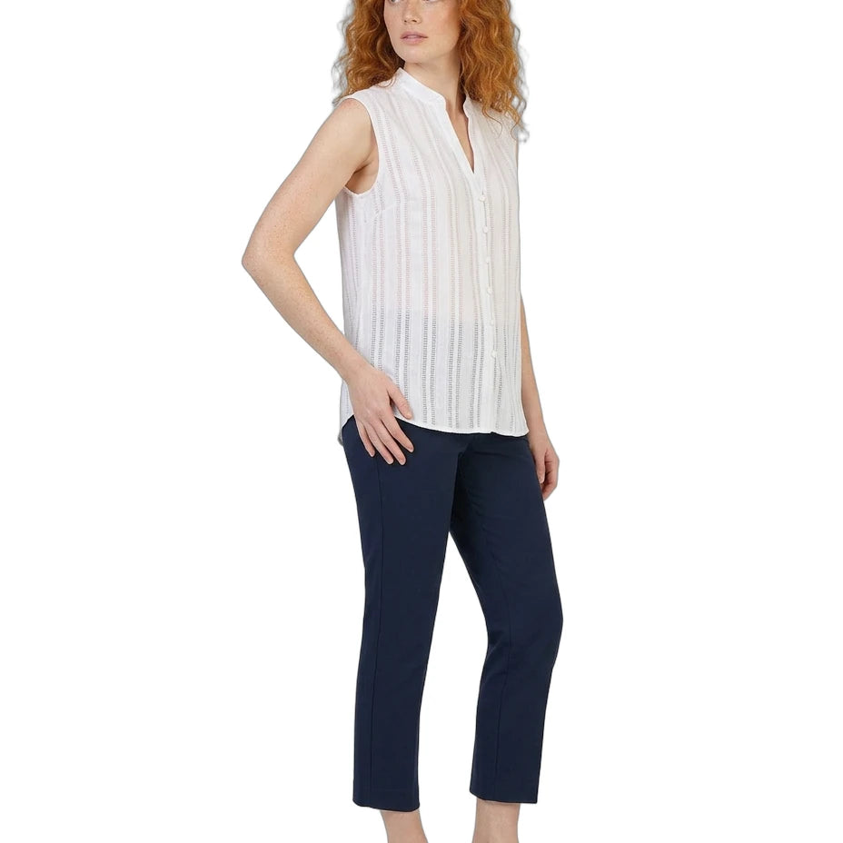 Woman wearing a white sleeveless Calvin Klein blouse and navy pants on a white background