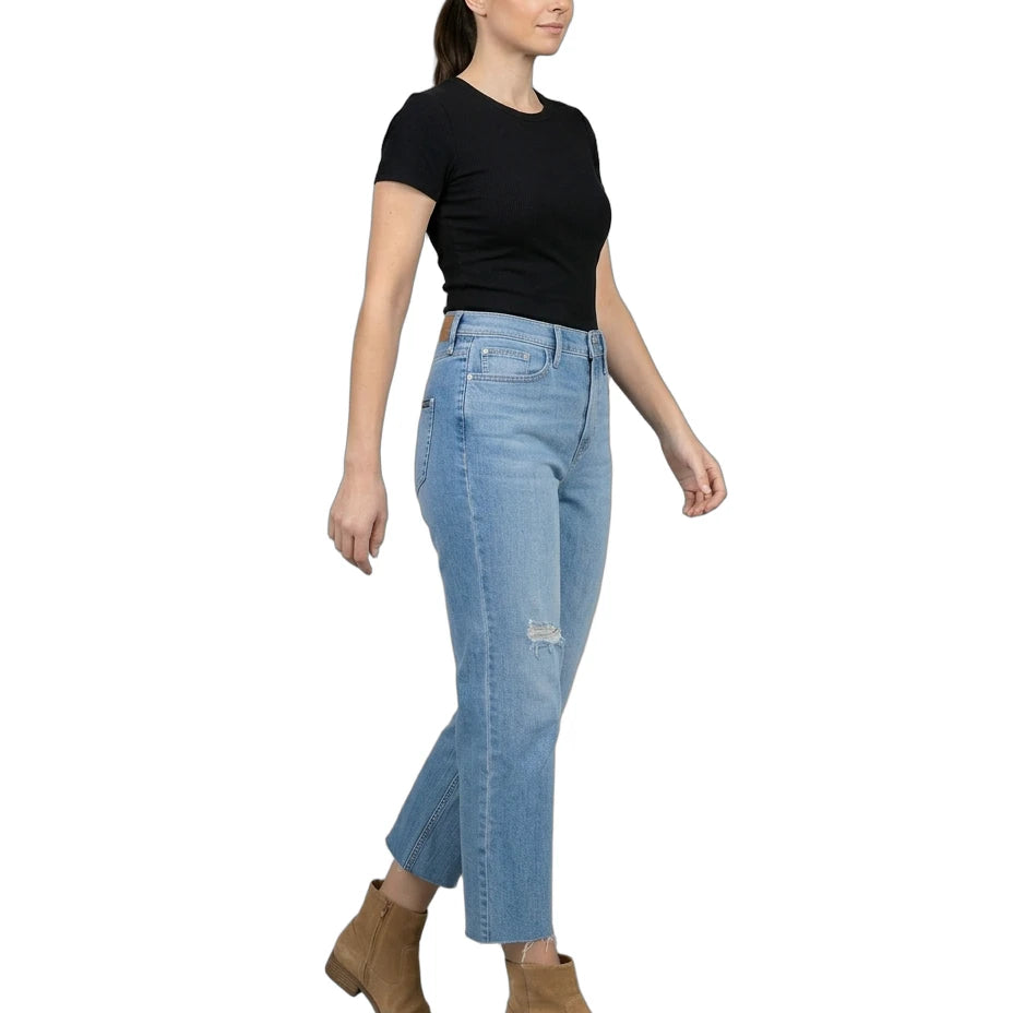 Woman wearing light blue jeans and a black top on a white background