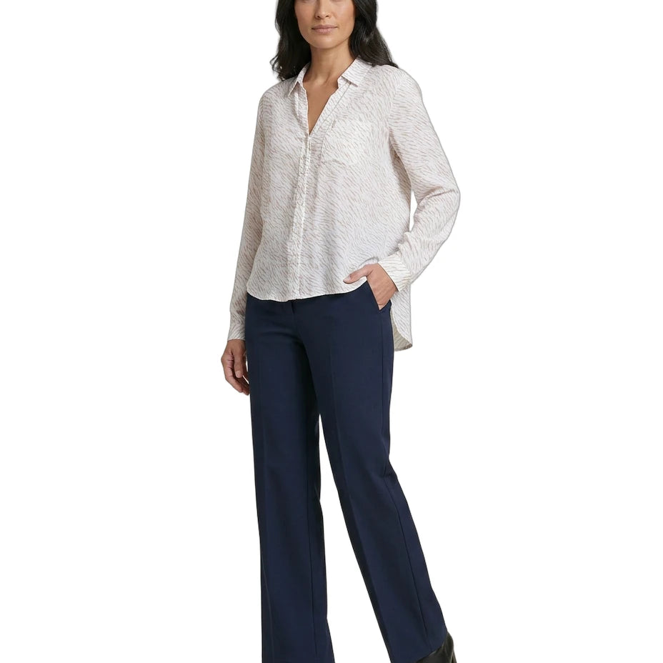 Woman wearing a white Calvin Klein blouse and navy pants on a white background
