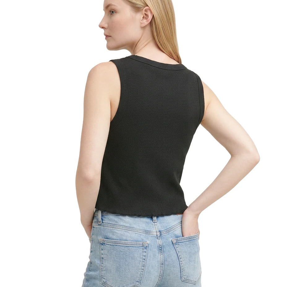 Woman wearing a black sleeveless top and light blue jeans on a white background