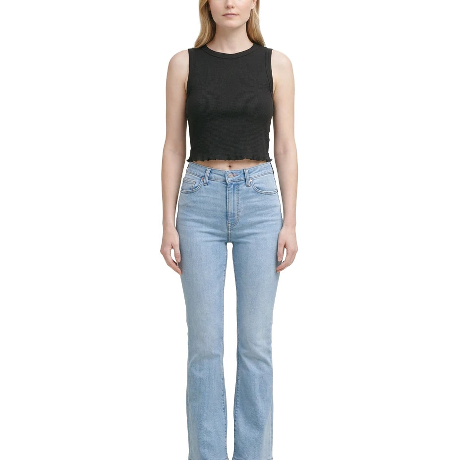 Woman wearing a black sleeveless top and light blue jeans on a white background