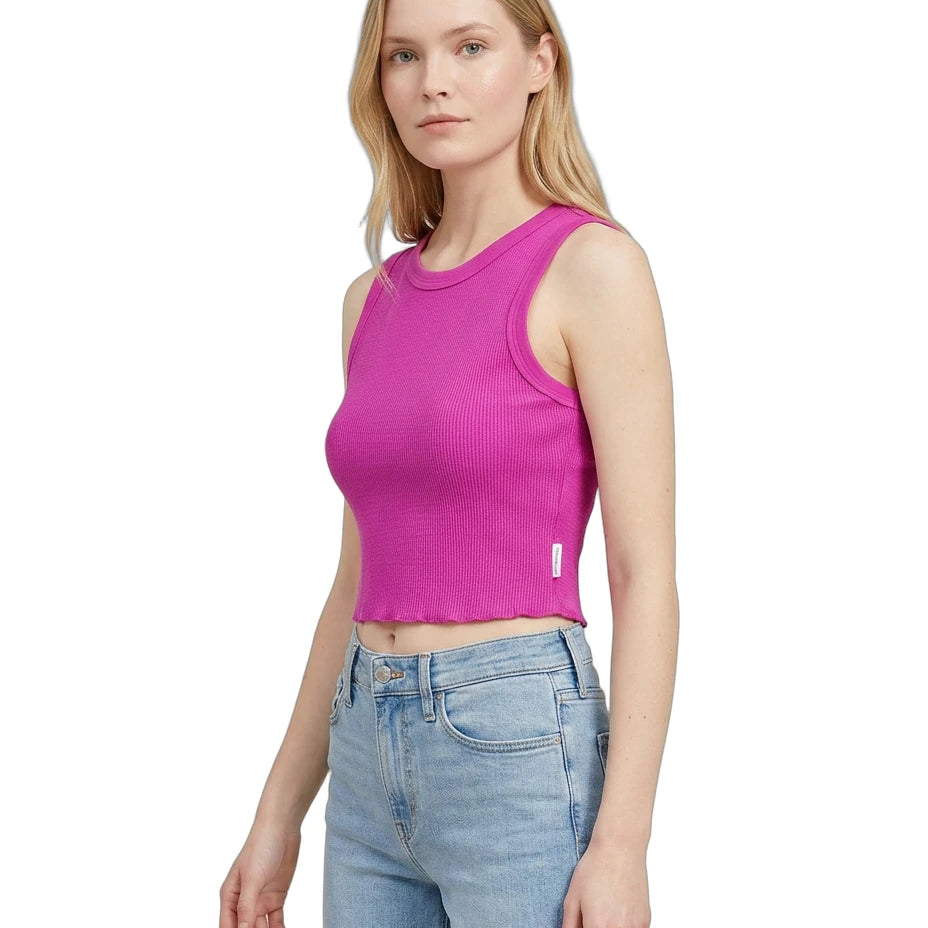 Woman wearing a bright pink tank top and light blue jeans on a white background