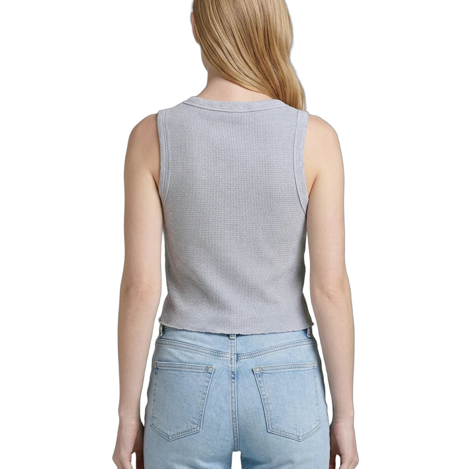 Person wearing a light gray sleeveless top and light blue jeans on a white background