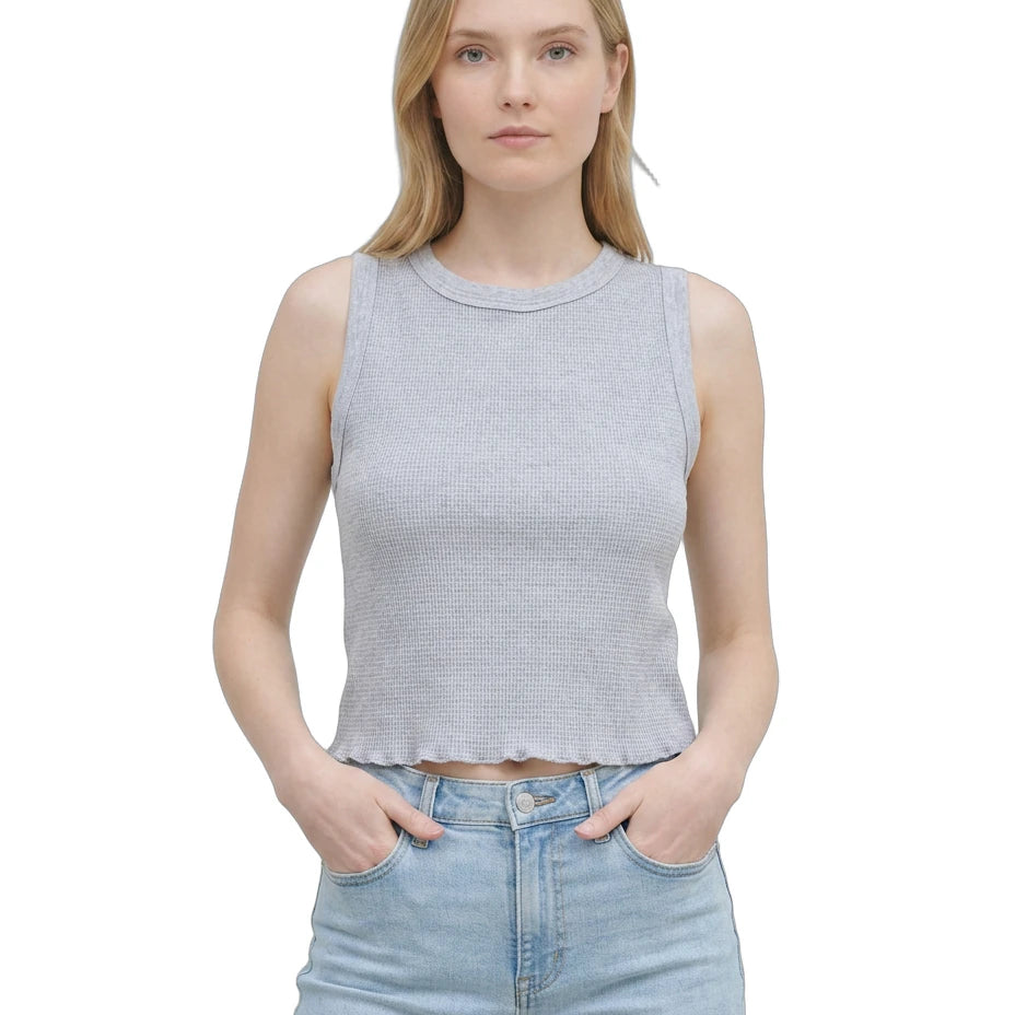 Woman wearing a sleeveless gray top and light blue jeans on a white background