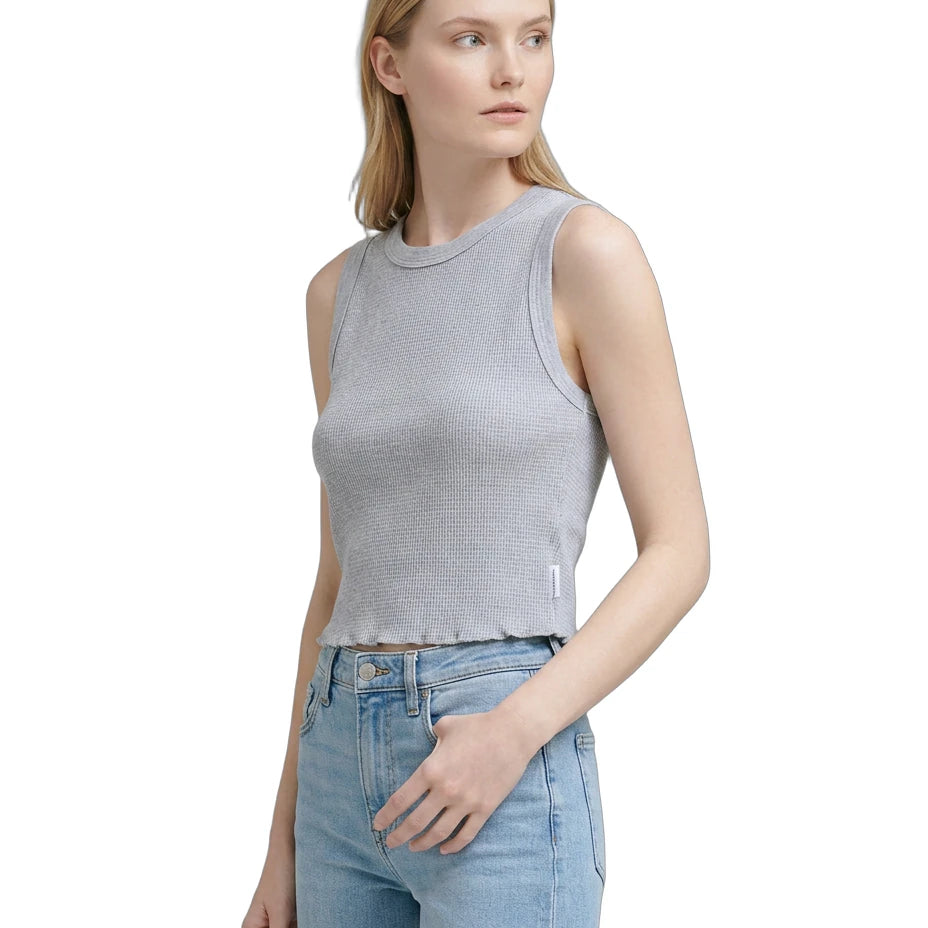 Woman wearing a gray sleeveless top and light blue jeans on a white background