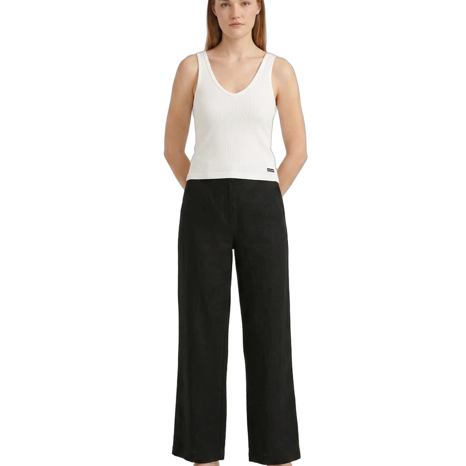 Woman wearing a white sleeveless Calvin Klein top and black wide-leg pants on a white background