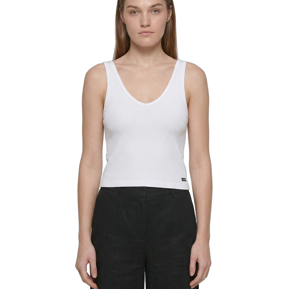 Woman wearing a white Calvin Klein tank top and black pants on a white background