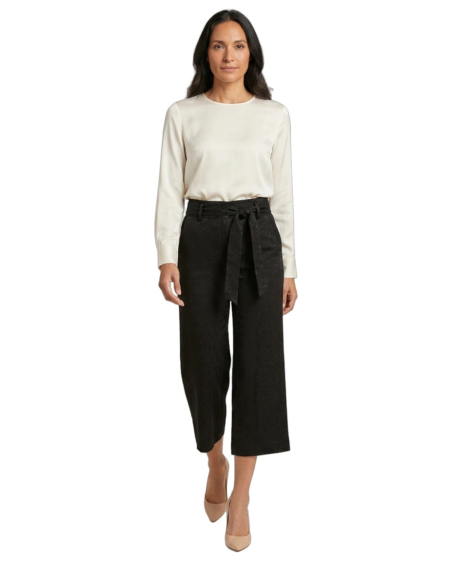 Woman wearing a white blouse and black Calvin Klein pants on a white background