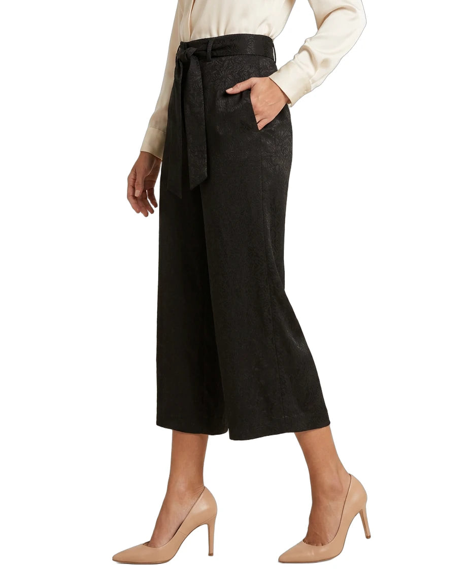 Person wearing black Calvin Klein wide-leg pants with a belt on a white background