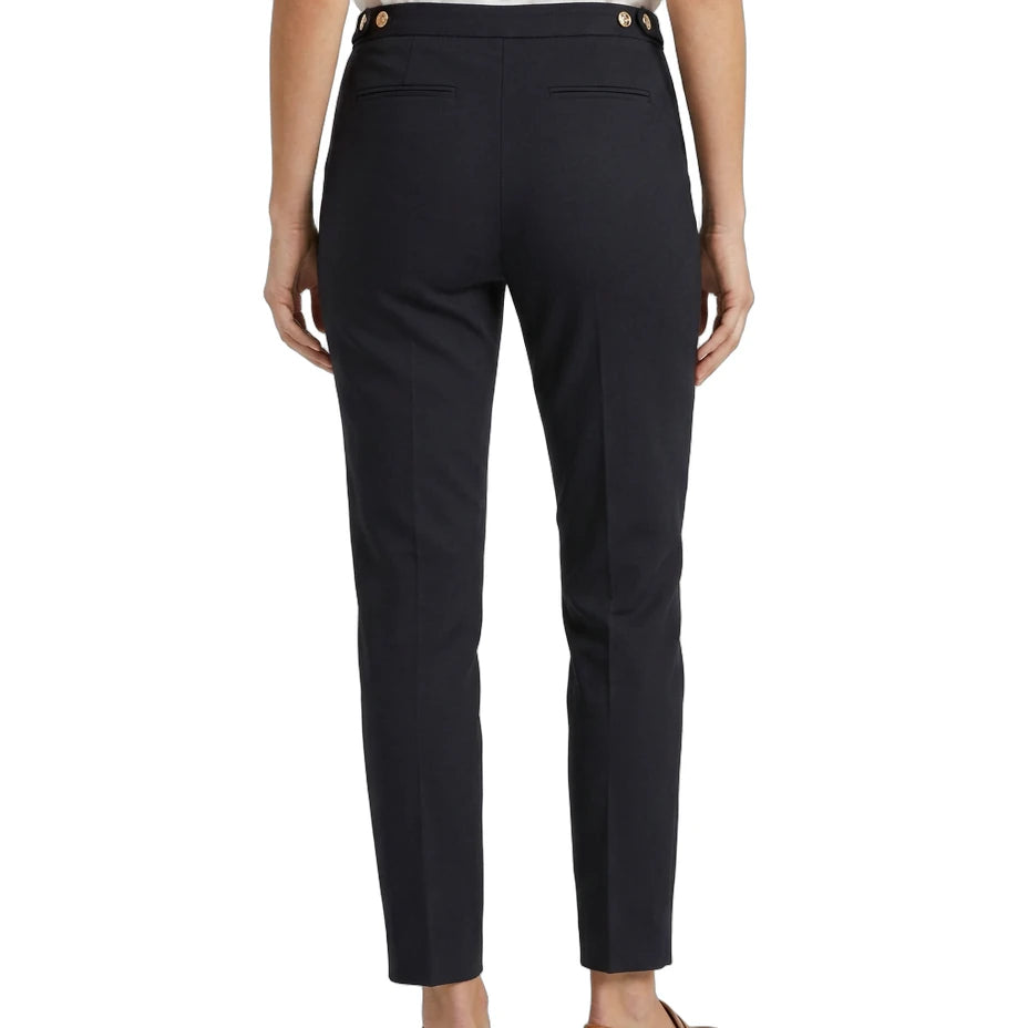 Person wearing navy Calvin Klein pants with gold buttons on a white background