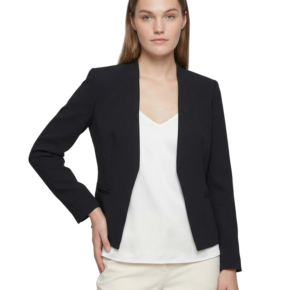 Woman wearing a navy Calvin Klein blazer over a white top and cream pants on a white background