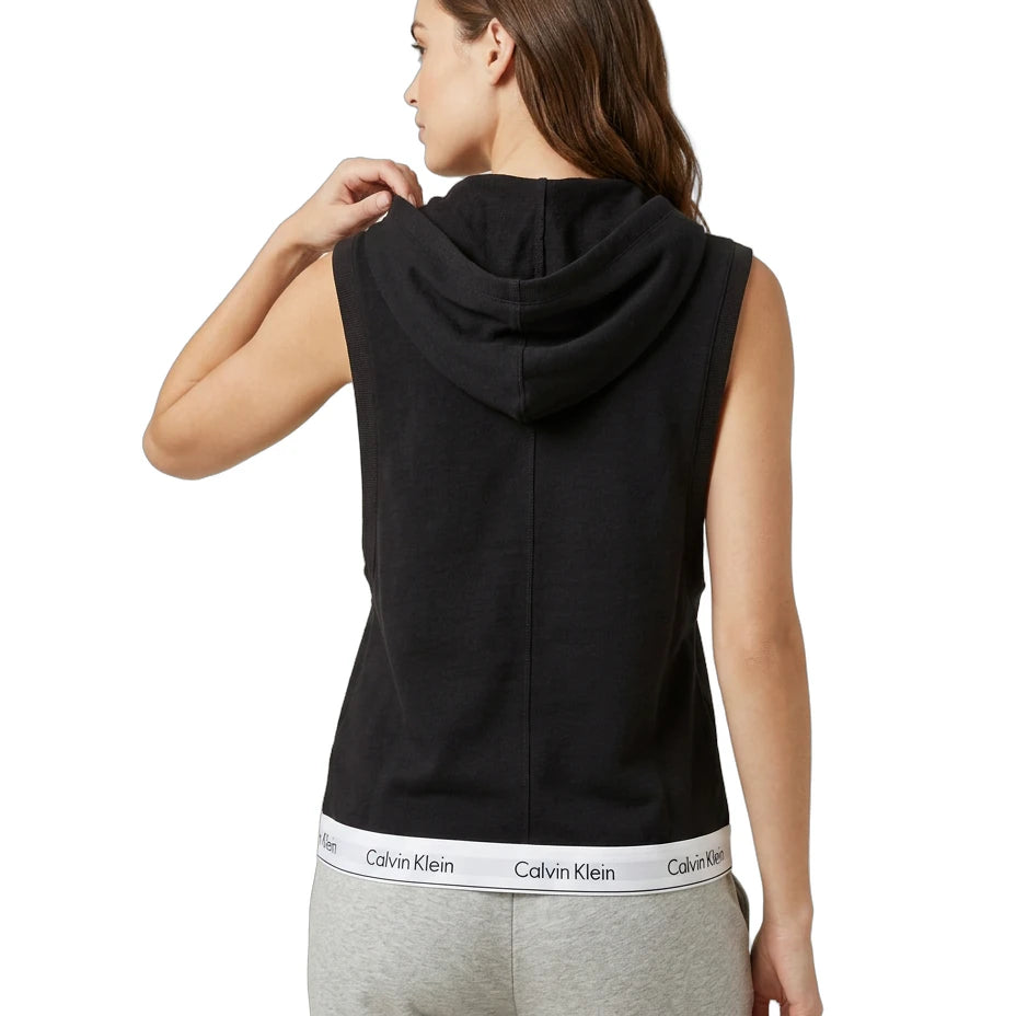 Woman wearing a black sleeveless hoodie with Calvin Klein logo on a white background