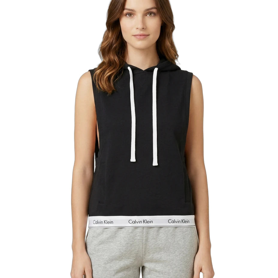Woman wearing a Calvin Klein black sleeveless hoodie with white drawstrings on a white background