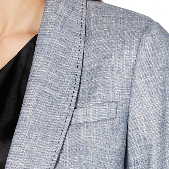 Close-up of a gray checkered Calvin Klein blazer on a person with a blurred background
