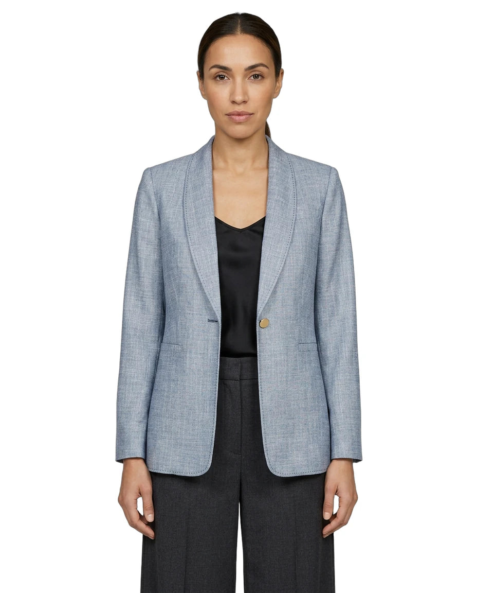 Woman wearing a light blue Calvin Klein checkered blazer over a black top on a white background