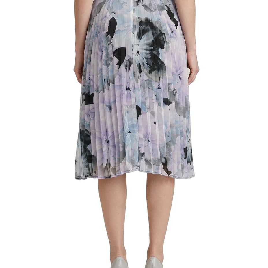 Person wearing a Calvin Klien pleated skirt with abstract floral pattern on a white background