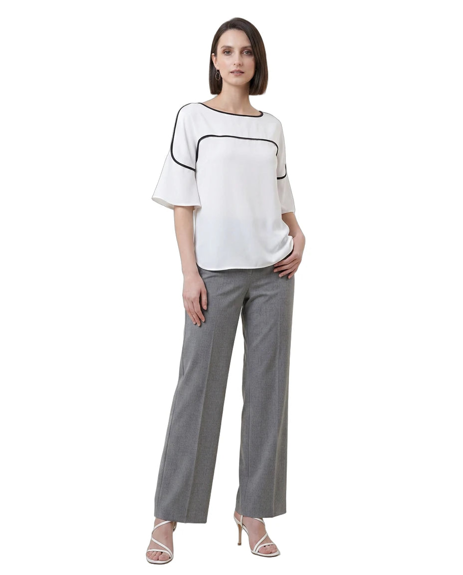 Woman wearing a white Calvin Klein blouse with black trim and gray pants on a white background