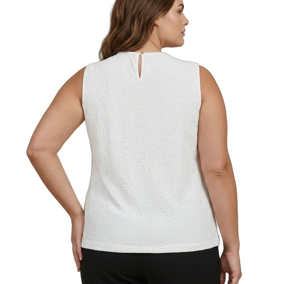Woman wearing a white sleeveless Calvin Klein top and black pants on a white background