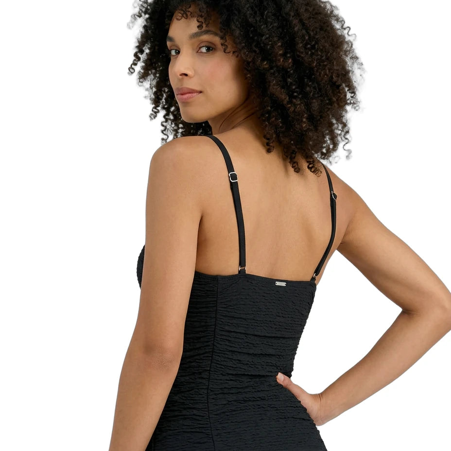 Woman wearing a black Calvin Klein tankini with thin straps on a white background