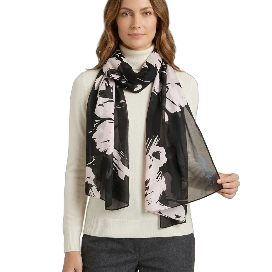 Woman wearing a black and white Calvin Klein floral scarf on a white background