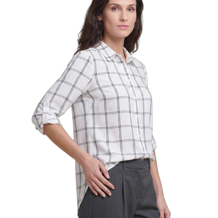 Woman wearing a white and black checkered Calvin Klein shirt with gray pants on a white background