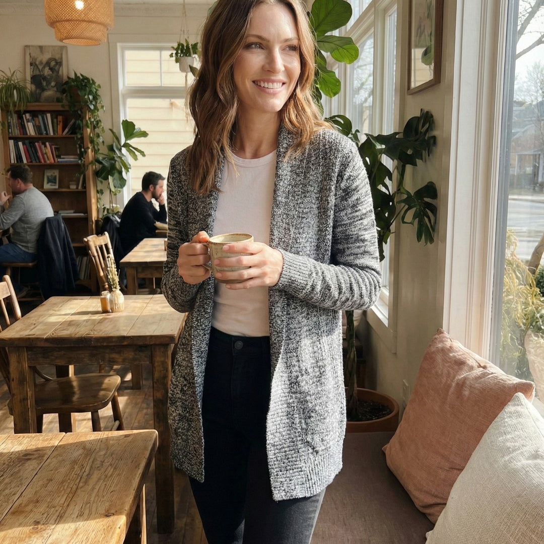Woman holding a cup in a cozy cafe with wooden tables and plants.