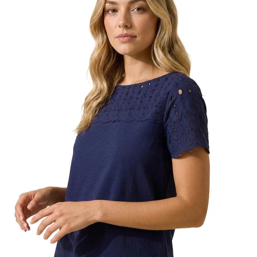 Three-quarter angle portrait of a woman wearing the Charter Club navy blue cotton short-sleeve top with floral eyelet embroidery across the chest and sleeves.