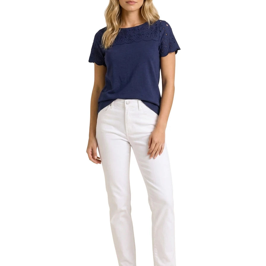 Full-length front view of a woman modeling a Charter Club navy blue eyelet-trim top paired with white slim-fit jeans and navy leather loafers.