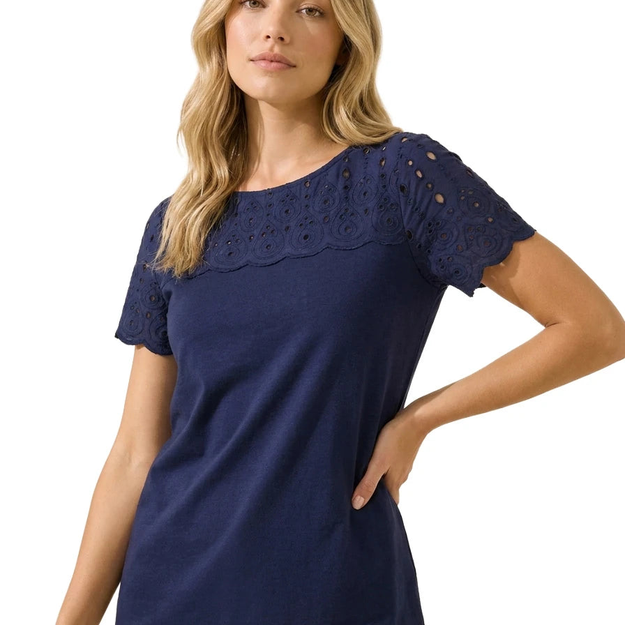 Front view of a blonde woman wearing the Charter Club women's petite navy blue cotton top with embroidered eyelet yoke and scalloped sleeves.