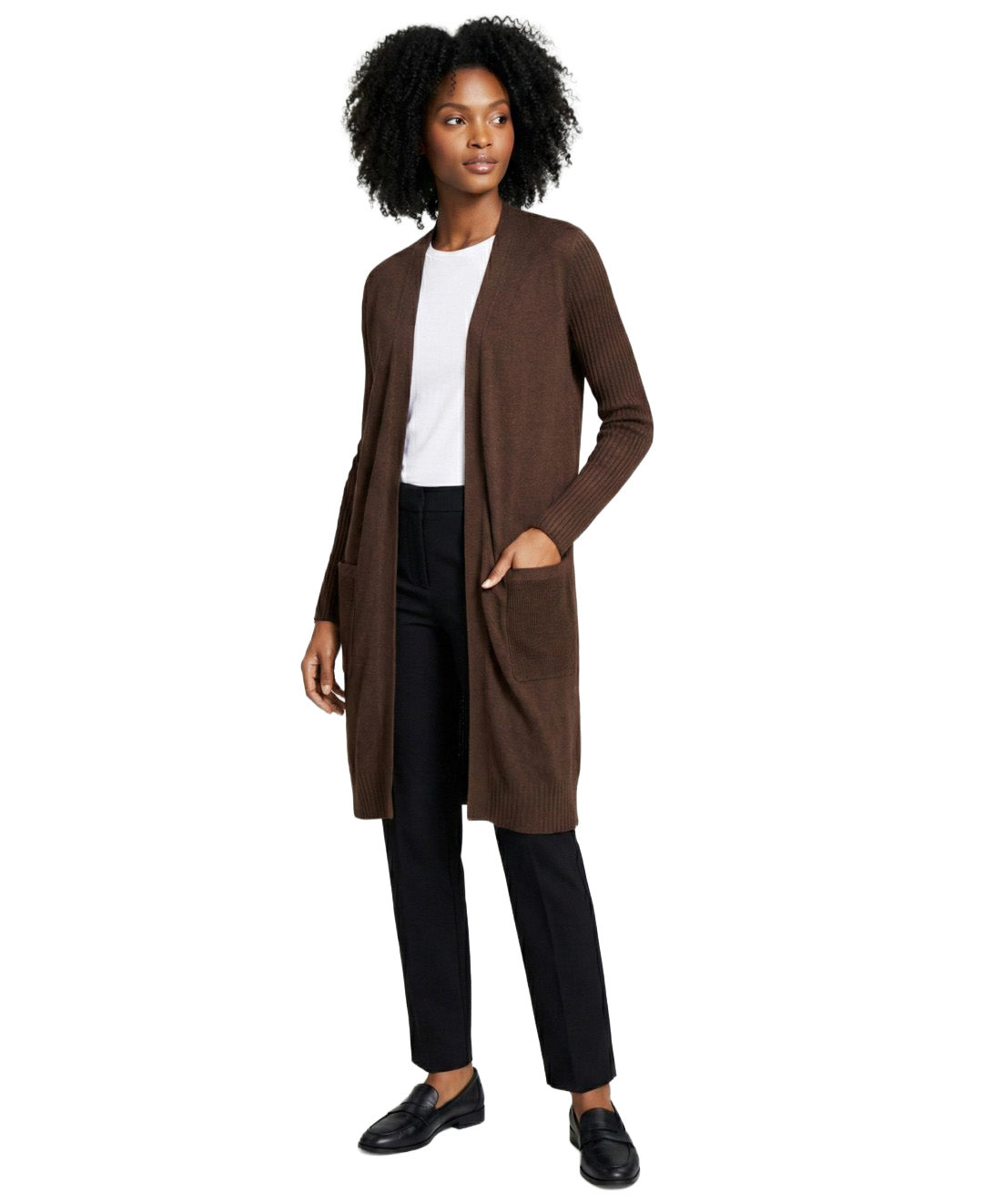 Woman wearing a brown cardigan over a white shirt and black pants on a white background
