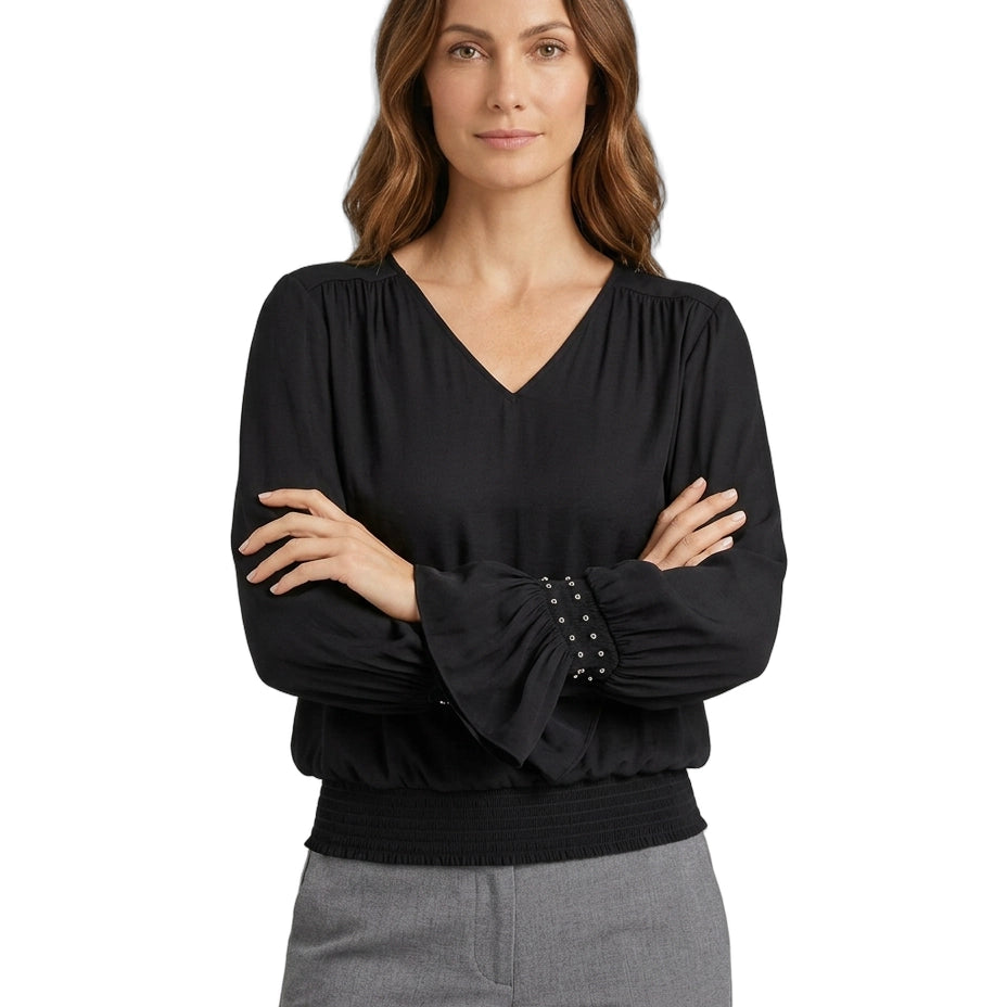 Woman wearing a black blouse with studded details on a white background