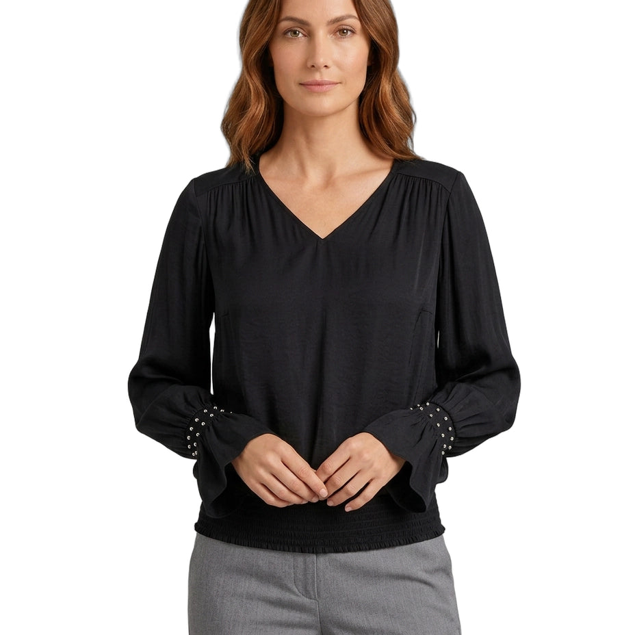 Woman wearing a black blouse with studded details on a white background