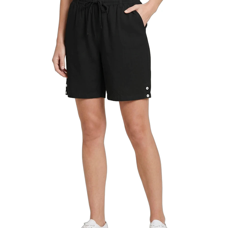 Person wearing black shorts with button details on a white background