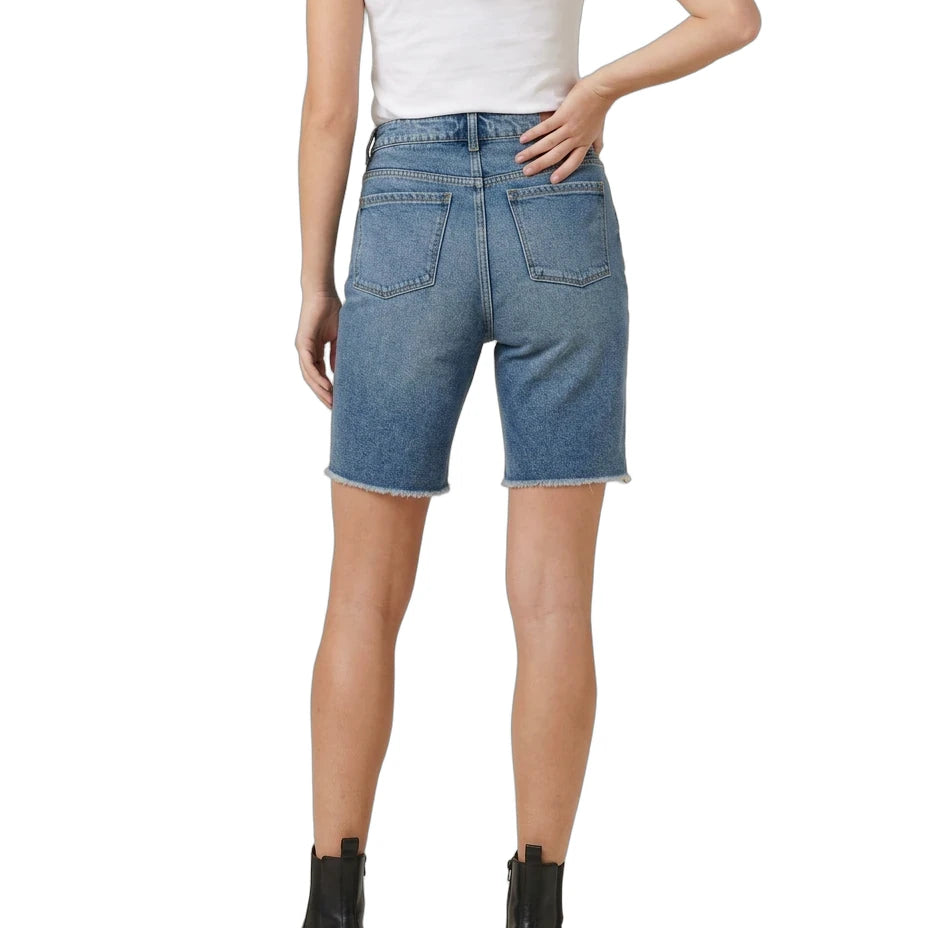 A model shown from the back wearing blue denim shorts with a raw hem, paired with a white t-shirt and black ankle boots, on a solid white background.