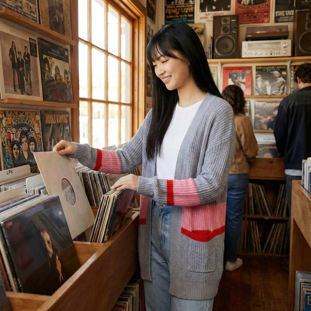 Woman browsing records in a record store with posters on the wall.