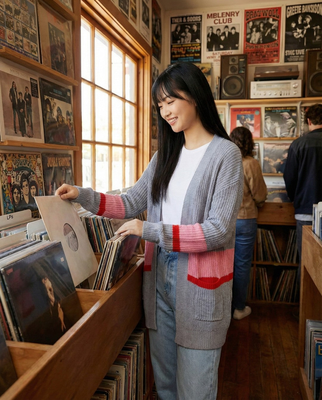 Woman browsing records in a record store with posters on the wall.