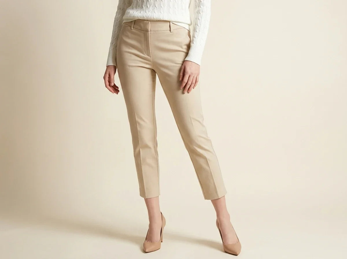 Cropped view of a woman modeling Charter Club beige ankle-length dress trousers paired with a cream cable-knit sweater and nude pointed heels[cite: 31].