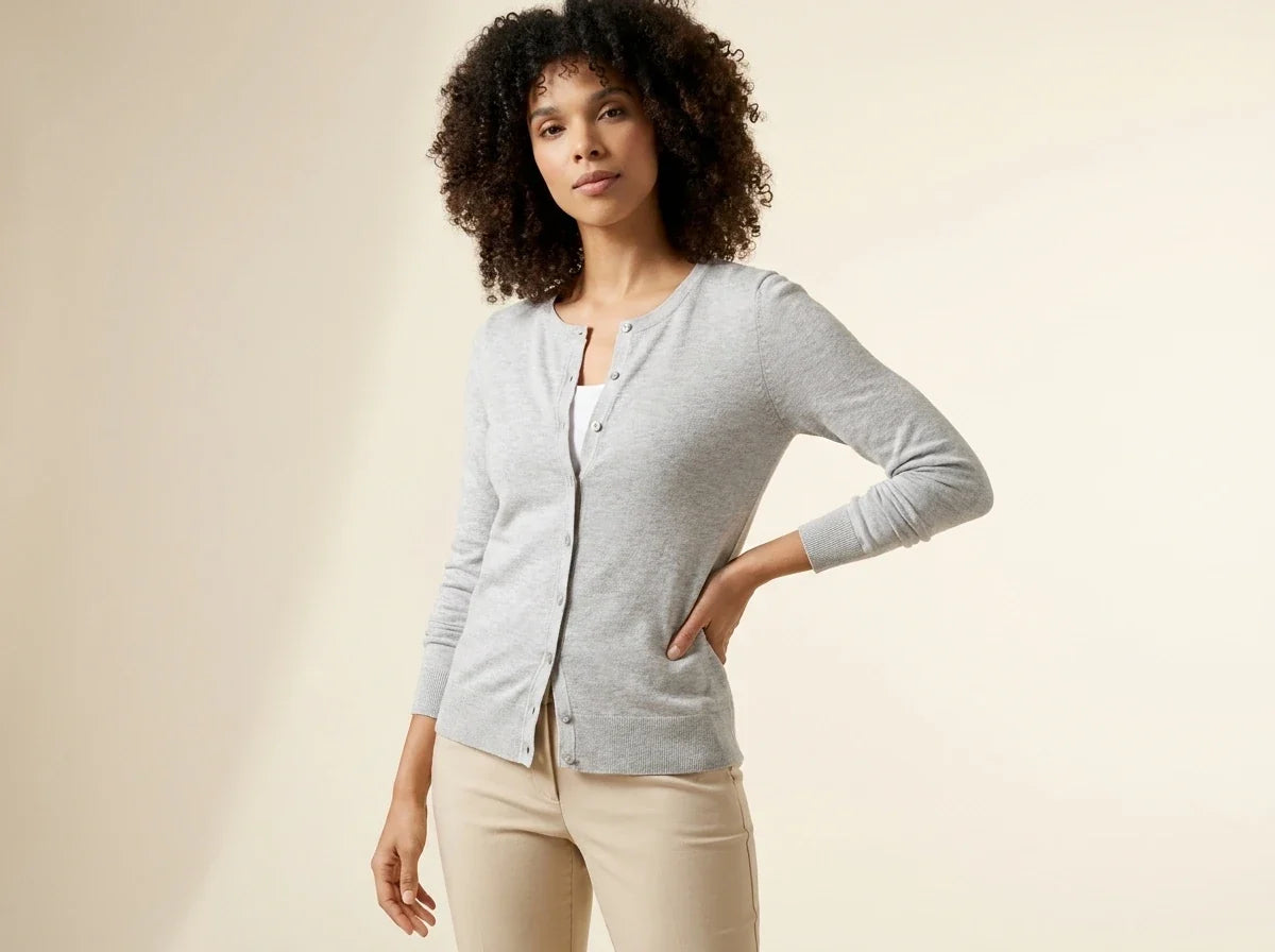 Woman with curly dark hair modeling a Charter Club light grey button-front cardigan sweater over a white top and beige trousers.