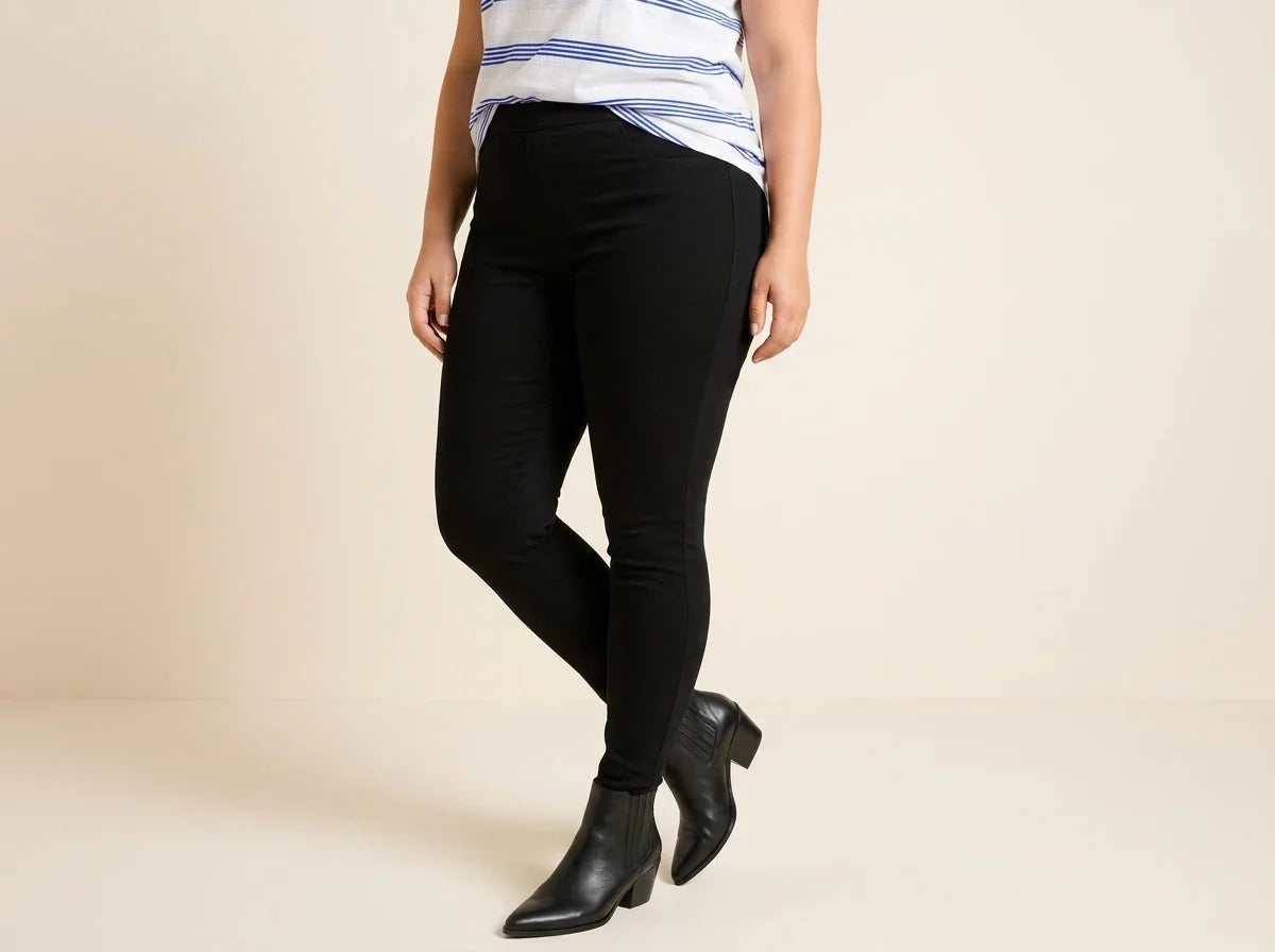 Cropped view of a woman wearing high-waisted solid black stretch leggings paired with black pointed-toe leather ankle boots and a striped top.