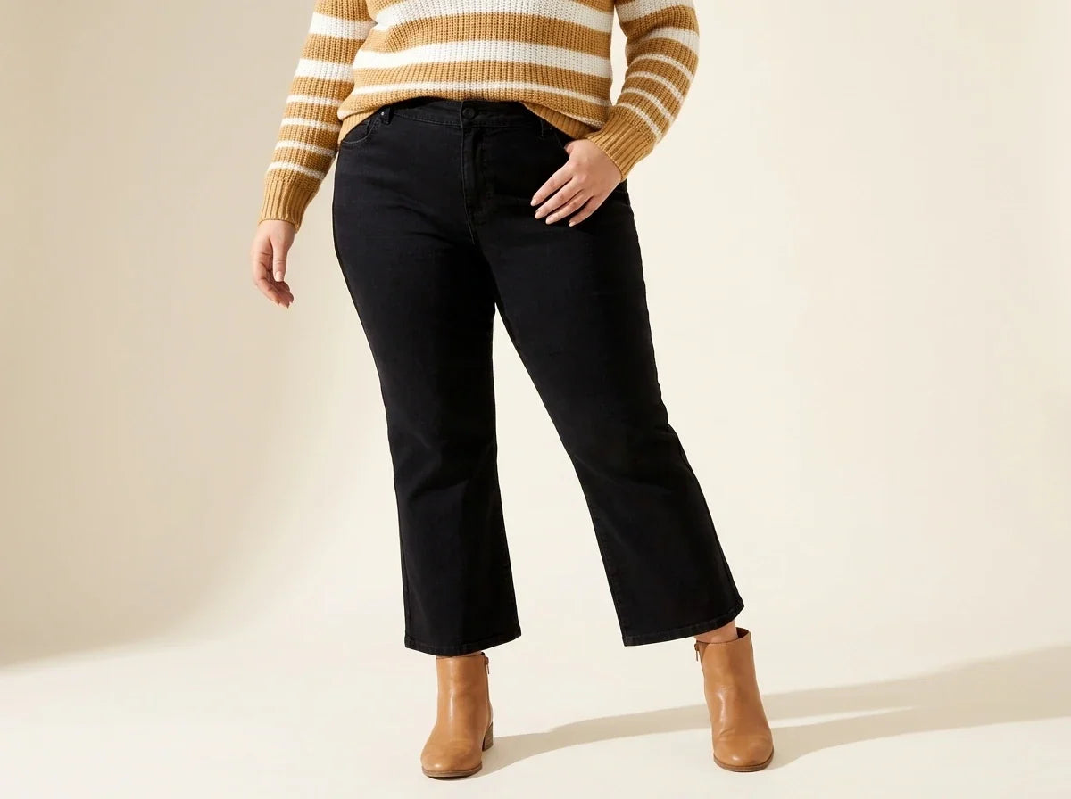 Cropped view of a woman wearing plus-size black cropped flare jeans with tan leather ankle boots and a striped sweater.
