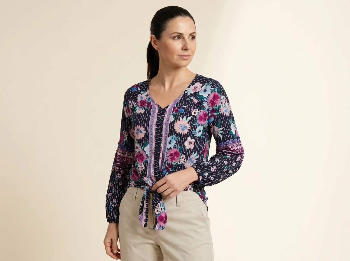 Brunette woman modeling a petite navy blue floral tie-front blouse with long balloon sleeves paired with beige chinos.