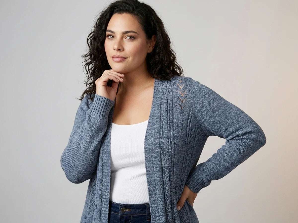A woman modeling a heathered slate blue open-front cardigan with lace-up detailing on the shoulder, worn over a white tank top and dark jeans against a neutral studio background.