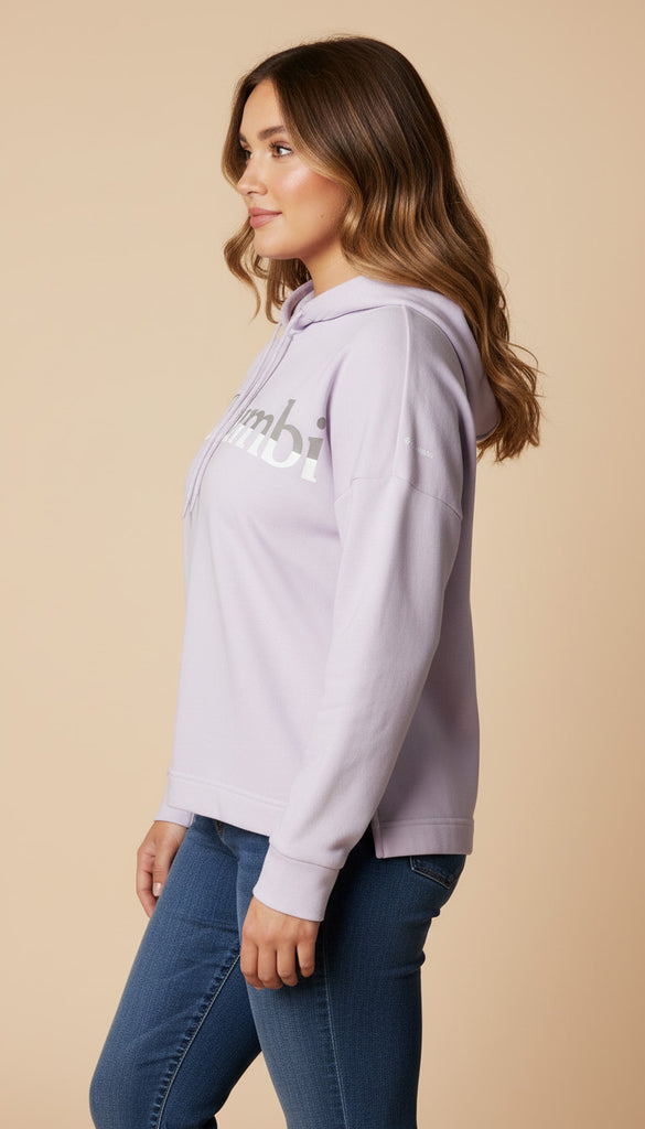 Woman wearing a light purple hoodie with a logo on a beige background