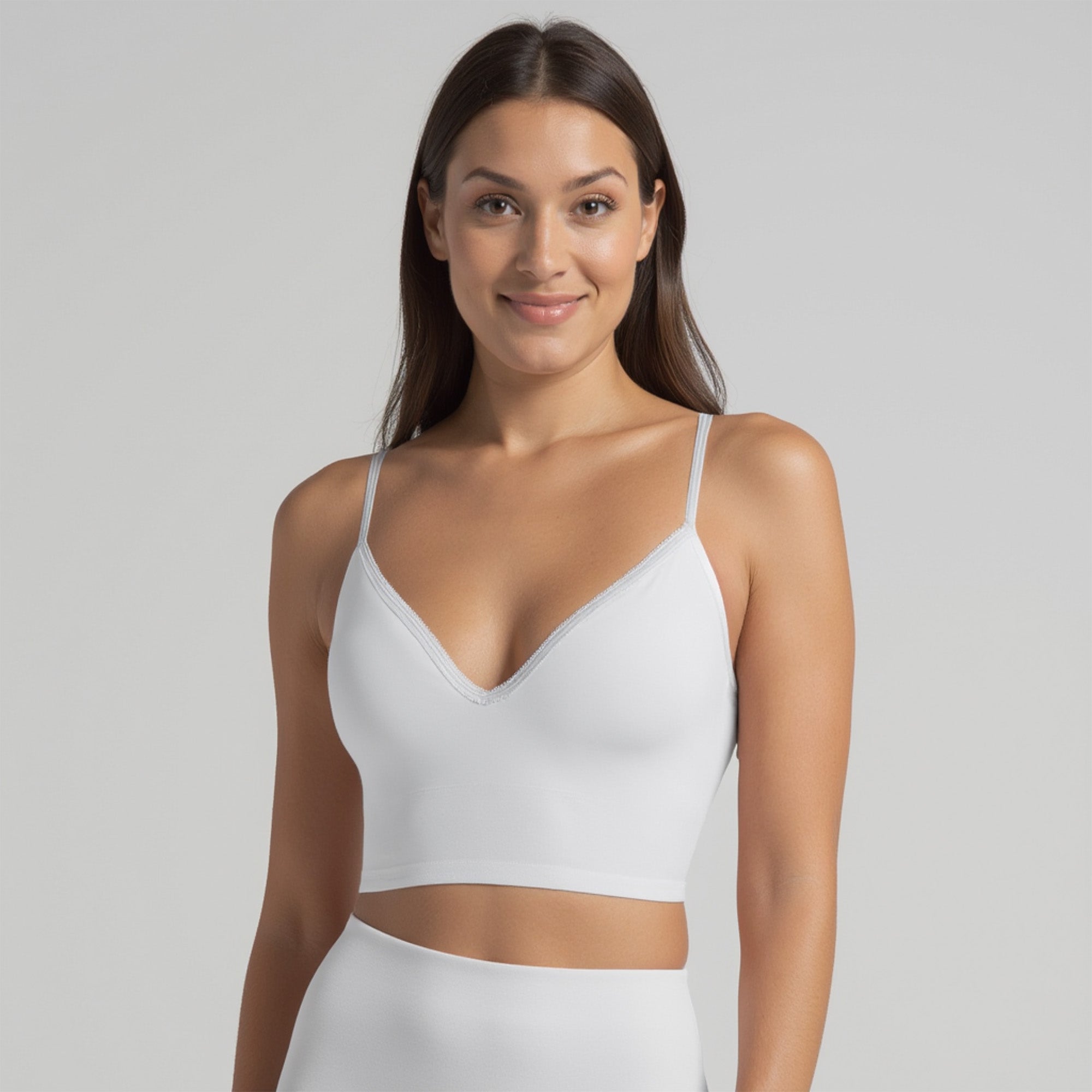 A woman wearing a white, solid-patterned bralette with a V-neckline and adjustable straps.