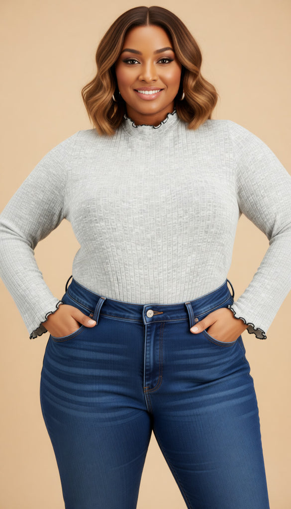 Woman wearing a gray sweater and blue jeans against a beige background