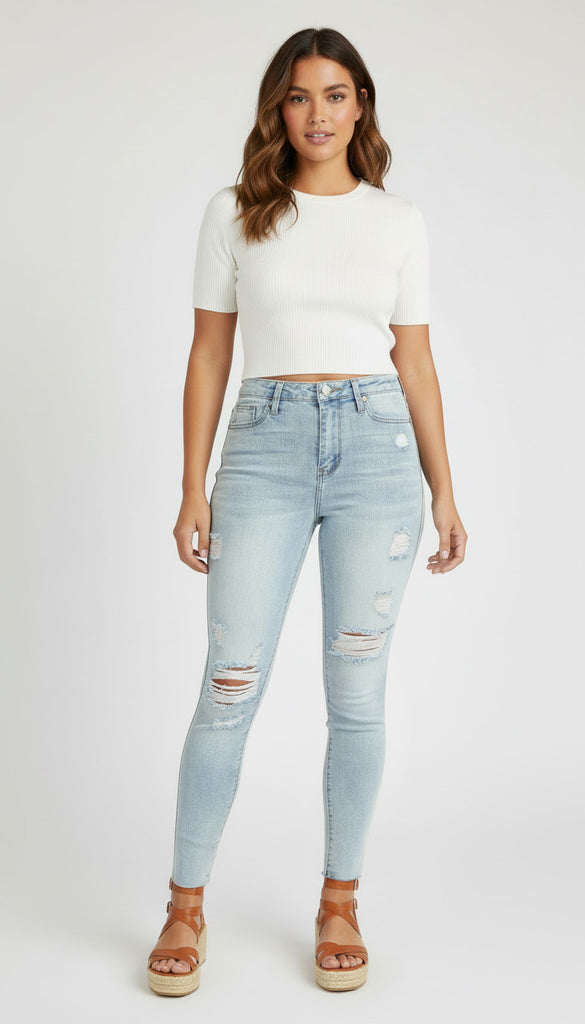 Woman wearing light blue ripped jeans and a white top on a white background
