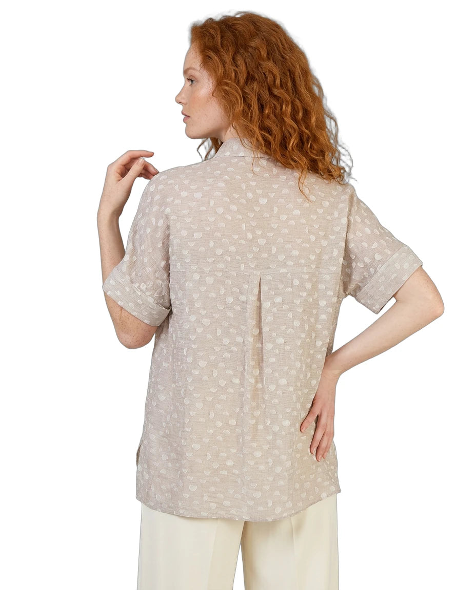 Woman wearing a beige patterned shirt on a white background